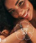 Smiling woman showcasing SPF 30 with Continuous Mist Spray With Protective Oil Formula for Beach Bum Essentials and Poolside Chill Sessions.