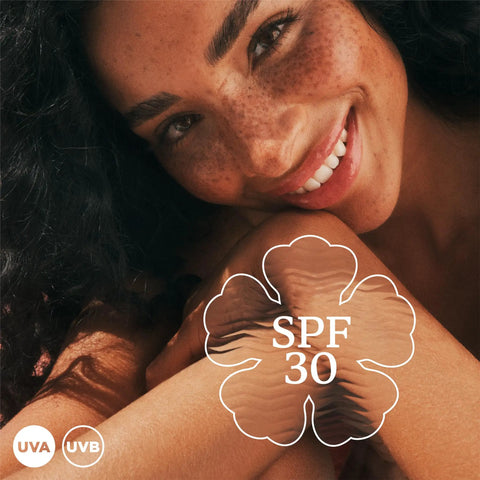 Smiling woman showcasing SPF 30 with Continuous Mist Spray With Protective Oil Formula for Beach Bum Essentials and Poolside Chill Sessions.