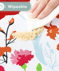 Close-up of hand wiping crumbs off flower print All-in-One Picnic Table Cover Set With Bench Covers For 6 Foot Tables.