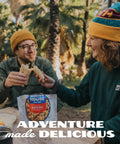 Two campers enjoying Gluten Free Korean Inspired Beef Freeze Dried Trail Ready Camping Meal For Backpackers at a forest setup.