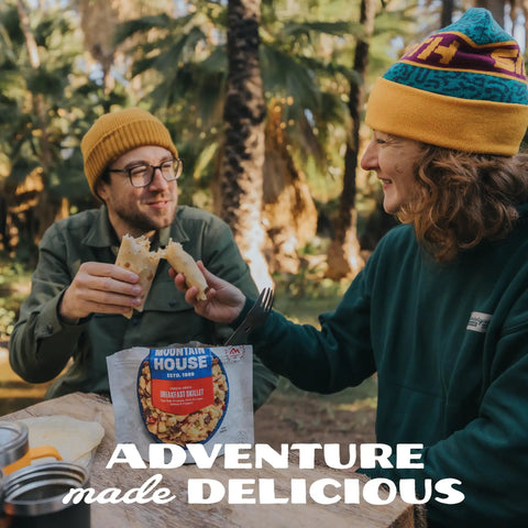 Two campers enjoying Gluten Free Korean Inspired Beef Freeze Dried Trail Ready Camping Meal For Backpackers at a forest setup.