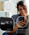 Woman using phone with Hidden Z-Wave Plus Smart Relay For Lights And Ceiling Fans, 120-277 VAC, 10A, Neutral Wire Required beside her.