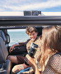 Woman holding 20 Oz Leakproof Stainless Steel Travel Bottle With Locking Lid in car at beach, ideal for coffee or water on the go.