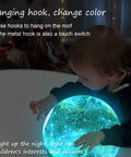 Child interacting with 7.9 Inch Large Moon Lamp With Galaxy Starry Surface, 16 Color Modes, Remote Control And Touch Sensor
