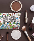 Geocaching Makeup Bag Gift For Her Just A Girl Who Loves Geocaching, surrounded by cosmetics on a brown background.