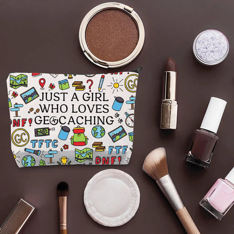 Geocaching Makeup Bag Gift For Her Just A Girl Who Loves Geocaching, surrounded by cosmetics on a brown background.