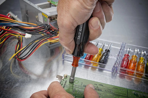 Person using 11 Piece Convertible Nutdriver Set With Piggyback Torque Amplifier Handle Color Coded Grips on circuit board