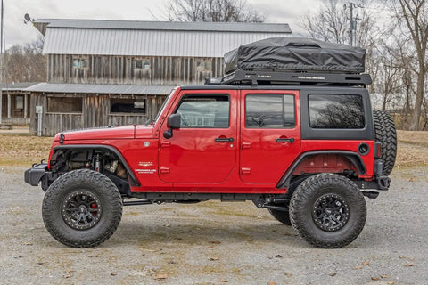 Red Jeep Wrangler JK 2007-2018 with off-road tires and roof rack, missing front bumper caps for stubby conversion.
