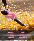 Cordless 20V Leaf Blower with 2.0Ah batteries and charger, 150 MPH turbo mode, dual speed, pink finish, blowing leaves on path.