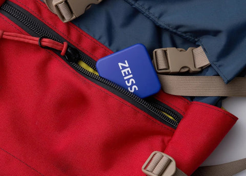ZEISS lens cleaning tin boxes with hinge lids, blue, pack of 4, tucked into a red backpack pocket.