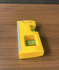 QERDIVO Spirit Levels Mini Horizontal Vertical Pockets Spirit Levels Spirit Bubble Leveler on wooden surface, compact yellow design.