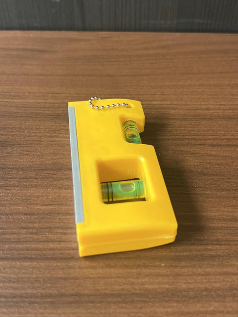 QERDIVO Spirit Levels Mini Horizontal Vertical Pockets Spirit Levels Spirit Bubble Leveler on wooden surface, compact yellow design.