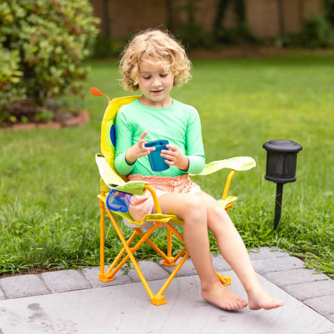 Child sitting in Giddy Buggy Kid-Sized Folding Lawn And Camping Chair With Cup Holder, water-resistant fabric, outdoors on patio.
