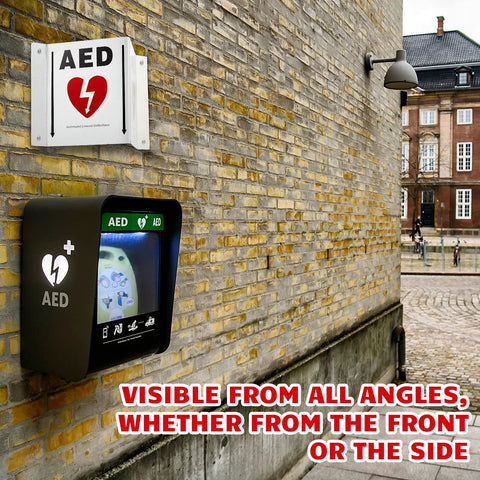 Kigley AED projection sign and portable cabinet mounted on brick wall; white sign with red heart and black cabinet with AED label.