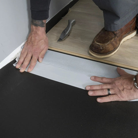 Person installing Straight Shooter Floor Underlayment For Laminate And Engineered Wood, 600 Square Foot Roll on black subfloor.