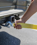 Person attaching Heavy Duty Tow Strap With Hooks, 2 Inch By 20 Foot, 10,000 Pound Capacity, Bright Yellow Polyester Webbing to vehicle hitch