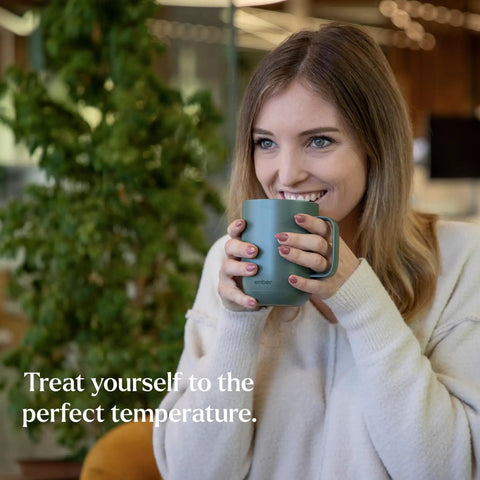 Keep Your Coffee Piping Hot With This App Controlled Smart Mug Featuring A 14Oz Rechargeable Heated Warmer Crisp Led Panel And On Point Temp Controls Total Game Changer For Desk Vibes And Daily Sessions In Fresh Sage Green, a woman happily holds a sage green heated coffee mug.