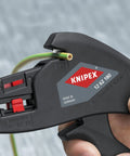 Hand using insulation strippers for wires compact automatic cable stripping tool on green cable, adjusts 0.2 to 6 mm²