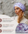 Woman wearing a reusable waterproof shower cap for women with nonslip silicone forehead strip, marble pattern, soft breathable durable cap.