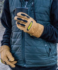 Person wearing Ranchworx Winter Work Gloves RWDI Premium Leather Insulated Cold Weather Gear holding cup on outdoor trail.