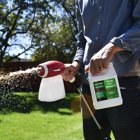 Person applying Liquid Soil Loosener and Conditioner for Compact Soils to lawn using a sprayer, 32 oz bottle visible
