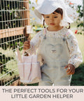 Child holding pink tote from Kid Friendly Garden Starter Kit With Durable Safe Tools For Outdoor Fun Including Gloves, Tote Bag, 22Oz Watering Can.
