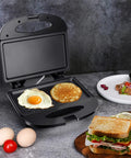Aigostar Flat Sandwich Maker With Nonstick Deep Grill Surface, Black. Eggs and pancakes cooking on the nonstick plates.