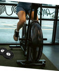 Person using exercise bike with Upgrade Your Home Gym With A Dope Heavy Duty Exercise Bike Belt Pulley Disc visible on right side.