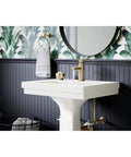 Low-Flow Brushed Bronze Single Hole Bathroom Faucet With Drain Assembly on a white pedestal sink in a modern bathroom.