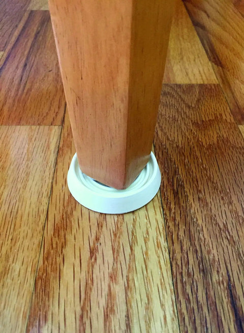 Super Grippy Rubber Furniture Cups To Kick Sliding And Scratching Away Straight Up Heavy Duty Floor Protectors For Chairs Tables And Caster Wheels Up To One And Half Inch Size With Easy Four Pack Setup under a wooden chair leg on hardwood floor.