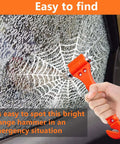 Close-up of bright orange 2-in-1 car window breaker hammer and seat belt cutter in hand next to a shattered window