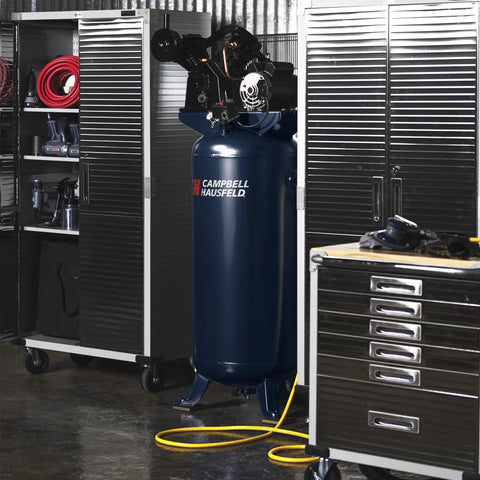 Heavy Duty Sixty Gallon Two Stage Air Compressor in workshop, showcasing oil lubricated cast iron pump and sturdy design.
