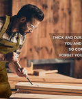 Kickass Heavy Duty Waxed Canvas Woodworking Apron For Men Featuring Boss Level Pocket Layout, worn by man chiseling wood.
