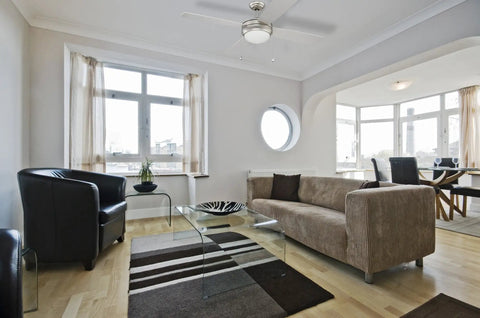 Laval 52 Inch Ceiling Fan With Light Kit in living room with brown sofa and large windows, brushed pewter finish, dual mount.