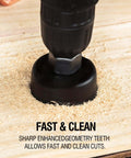 Hole saw bit on a drill cutting into wood, black metal cutter with wood shavings.