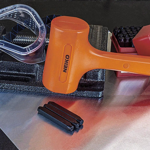 4 Lb Neon Orange Dead Blow Hammer With Unibody Molded Construction on metal sheet with tools, focus on checkered grip.