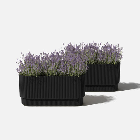 Long Planter For Porch Patio And Backyard In Durable Plastic Stone Composite Fluted All Weather Outdoor Pot For Shrubs And Flowers Modern Decor With Scratch And UV Resistant Finish displayed with plants.
