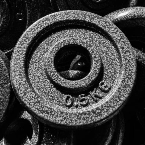 Close-up of cast iron weight plate with 0.5 kg marking, part of Eight Piece Cast Iron Weight Plates For Barbells 9.5 Cm Diameter 26 Mm Center Hole 8 Plate Set Durable Home Gym Fitness Weights Reliable Performance Compatible With Standard Barbell.