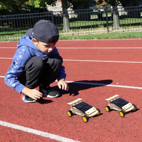 Child playing with two solar-powered cars from Hands On Solar And Wind STEM Kits For Kids Aged 8 9 10 11 12 Build A Solar Car Plane Wind Powered Car And Electric Fan This Cool And Fun Science Set For Family Bonding And Real World Learning For Boys And Girls Gift on a track