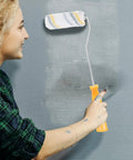 Ready To Roll Mini Paint Roller Brush Kit With Quick Swap Covers For Doors Baseboards And Window Trim Professional Wall Painting Tool That Makes Painting A Breeze, shown in use by a smiling individual.