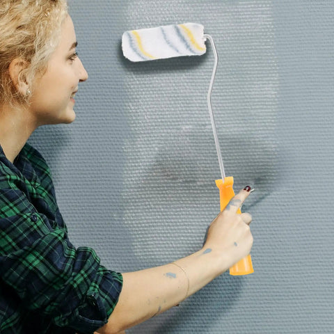 Ready To Roll Mini Paint Roller Brush Kit With Quick Swap Covers For Doors Baseboards And Window Trim Professional Wall Painting Tool That Makes Painting A Breeze, shown in use by a smiling individual.