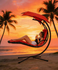 Woman relaxing in Freestanding Arc Stand Hanging Chaise Lounge Swing Chair With Curved Steel Frame against sunset by the beach.