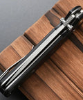 Folding Knife With 14C28N Steel Blade And Carbon Fiber Handle Go To EDC Knife With Pocket Clip shown folded on wood