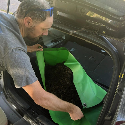 Person placing Beefed Up 3x3 Ft Green Heavy Duty Tarp Waterproof UV Resistant PFAS Free Cover into car trunk