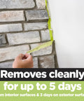 Person removing Rough Surface Industrial Tape 0.94 In By 60 Yd Heavy Duty Adhesive from stone wall demonstrating clean removal
