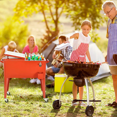 Outdoor party scene with 80 Quart Rolling Cooler Ice Chest With Wheels And Bottle Opener in red next to a barbecue.