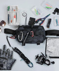 Water Resistant Outdoor Chest Bag For Men With Lightweight Tactical Design For Running Cycling Hiking And Workouts EDC Ready Chest Pack With Durable 600D Oxford Fabric Quick Access Pockets Black Camo surrounded by outdoor gear like gloves and tools.