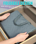 Person placing folded Roomy 105L Extra Large Storage Bag For Blankets Bedding And Clothes 3 Pack With 4 Handles into wooden drawer