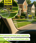 View from inside a car of a yellow "Slow Down This is a Neighborhood Not a Racetrack" sign on a street with houses.