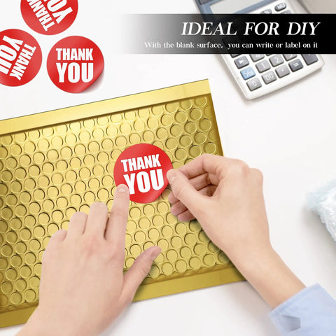 Hands placing a thank you sticker on a Gold Bubble Mailers 6x10 For Jewelry And Makeup Supplies 50 Pack Metallic Envelopes With Strong Self Adhesive Seal Waterproof Padding Durable Bulk Mailers That Look Luxe And Ship Safe on a desk.